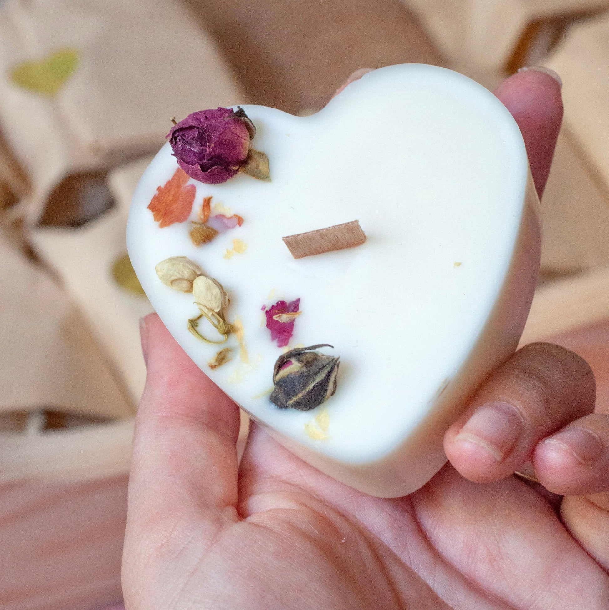 Une bougie en forme de cœur Décorer deux boutons de rose séchées et de fleurs de jasmin séchées.